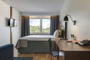 a hotel room with a bed and a desk and a window at Quality Hotel Grand, Borås in Borås