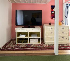a living room with a tv and a dresser at 一棟貸し宿ゲストハウスサンク in Masuda