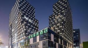 zwei hohe Gebäude mit einem Schild auf dem Dach in der Unterkunft Green Tree Inn Suzhou Wujiang East Tai Lake Tourism Resorts in Suzhou