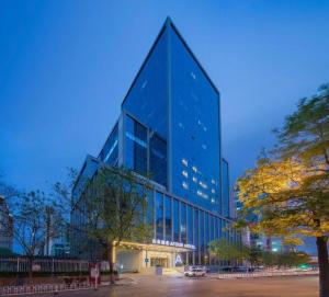 a tall blue building with cars parked in front of it at Atour Hotel Taiyuan Inner Ring in Taiyuan
