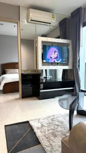 a living room with a bed and a tv on a wall at Modern Bangkok Apartment Train Access in Bangkok