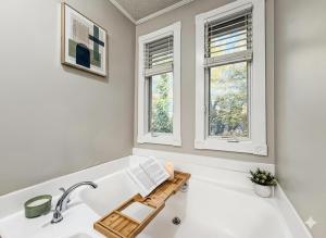 eine Badewanne mit einem Holztablett darauf neben zwei Fenstern in der Unterkunft King Bed Soaking tub, Yard with Screen Patio, Near ATL in Tucker + 40 Fotos