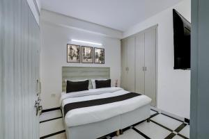 a white bedroom with a bed and a flat screen tv at Super Hotel O DLF Phase 1 Metro Station Gurugram in Gurgaon
