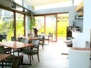 ein Restaurant mit Holztischen und -stühlen und Fenstern in der Unterkunft Corredor Yugawara Dog＆Resort in Miyakami