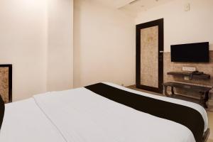a bedroom with a white bed and a television at Hotel O Vatva Railway Station Formerly Anmol Palace in Ahmedabad