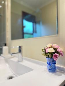 Um vaso azul com flores rosas sobre a pia do banheiro. em Whispering Pines em Kaihinu