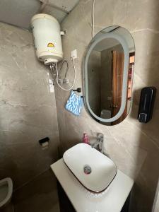 Un baño con un lavabo blanco y un espejo. en The Realm of ShivaShiv, en Rājpur