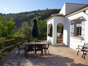 un patio con mesa, sillas y sombrilla en Casa Mari Carmen, en Cómpeta