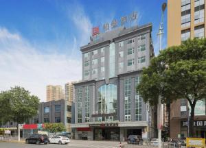 ein großes Gebäude, vor dem Autos parken in der Unterkunft Borrman Hotel Dongguan Houjie Wanda Plaza Liaoxia Metro Station in Dongguan