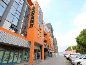 ein orangefarbenes Gebäude an einer Straße mit geparkten Autos in der Unterkunft Green Tree Inn Jiangsu Changshu Southeast Yuyue Square in Gujiashuigou