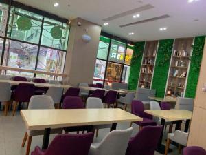 un restaurant avec des tables, des chaises et des murs verts dans l'établissement Lavande Hotel Shenzhen East Gate Wanxiang City Guomao Metro Statipn, à Shenzhen