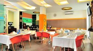 a restaurant with white tables and red chairs at Savali Hotel in Kampungdurian