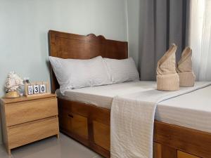 Bett mit einem Kopfteil aus Holz neben einem Nachttisch in der Unterkunft Surfers Shell Dahican in Dahikan