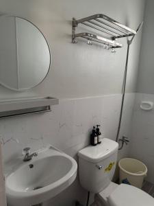 ein Badezimmer mit Waschbecken, Toilette und Spiegel in der Unterkunft Surfers Shell Dahican in Dahikan