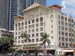 a large white building with palm trees in a city at Hedong Hotel in Shenzhen