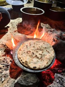 a pizza is cooking on a grill with fire at Jaisalmer Hostel Camel Castle & Safari in Jaisalmer