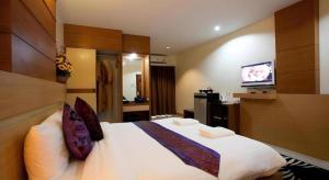 ein Hotelzimmer mit einem großen weißen Bett und einem TV in der Unterkunft Amnauysuk Hotel in Ban Si Than