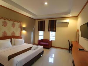 ein Hotelzimmer mit einem Bett und einem Stuhl in der Unterkunft Thada Chateau Hotel in Ban Bu Lamduan