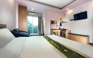 ein Hotelzimmer mit einem großen Bett und einem Fernseher in der Unterkunft The Loom Rangsit in Ban Lam Phak Kut