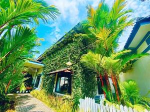 a house with palm trees in front of it at Forever Green Resort in Ấp Nhứt (1)