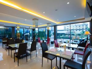 ein Restaurant mit Tischen und Stühlen und Fenstern in der Unterkunft UDTel Boutique Hotel Udonthani in Ban Dong Kheng