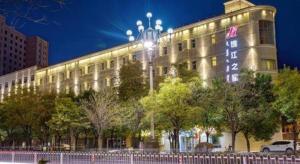 a large building with a lit up sign on it at Jinjiang Inn Baotou Donghe East Railway Station in Baotou