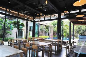 ein Restaurant mit Tischen und Stühlen und einem Pool in der Unterkunft Eco Moment Beach Resort in Ban Laem Phak Bia (1)