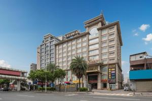 ein großes weißes Gebäude mit Palmen vor einer Straße in der Unterkunft Fu Yuan Hotel in Dongguan