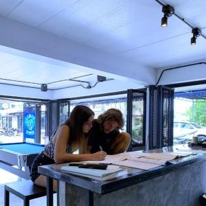 Dos mujeres sentadas en una mesa mirando los papeles. en Czone Hostel, en Ko Tao