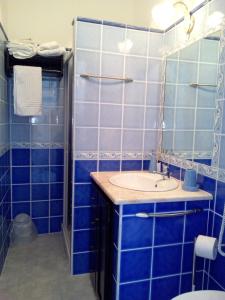 baño de azulejos azules con lavabo y aseo en B&B Historia Magistra, en SantʼAntìoco