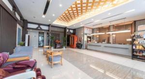 a living room with a blue couch and a kitchen at Jinjiang Inn Suqian Xiangwang Hometown Xingfu South Road in Suqian