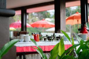 ein Tisch mit Geschirr und Sonnenschirmen in einem Restaurant in der Unterkunft Poochommhok Resort in Sangkhla Buri