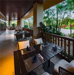 ein Restaurant mit Holztischen und Stühlen und Bäumen in der Unterkunft Country Garden Hot Spring Hotel Huizhou in Huizhou