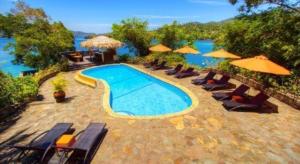 - une piscine avec des chaises et des parasols au bord de l'eau dans l'établissement Bastianos Lembeh Dive Resort, à Airtembago