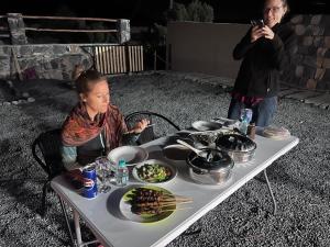 una mujer sentada en una mesa con un plato de comida en قبة سماء جبل شمس - qubat sama jabal shams, en Jebel Shams