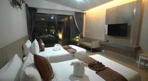 a hotel room with two beds and a television at Chatnipa Beach Resort in Klaeng
