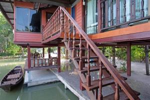 ein Haus mit Holztreppe neben dem Wasser in der Unterkunft Raknatee Resort in Ban Tha Chang (1)
