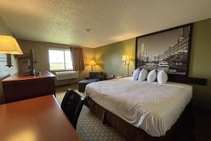 a hotel room with a bed and a desk at Super 8 by Wyndham Pontiac in Pontiac