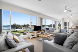 a living room with couches and a tv and windows at The Rotunda, Gerroa in Gerroa