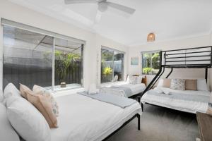 a white bedroom with two beds and a window at The Rotunda, Gerroa in Gerroa