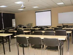 une salle de classe avec des tables, des chaises et un écran blanc dans l'établissement Jinjiang Inn JiNan Daminghu New Scenic Area Lishan Road, à Jinan