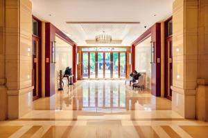 eine Lobby mit einer Person, die in einem Gebäude auf einem Stuhl sitzt in der Unterkunft Hainan Yatai Hot Spring Hotel in Haikou + 270 Fotos