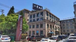 ein großes Gebäude mit auf einem Parkplatz abgestellten Autos in der Unterkunft Jinjiang Inn Shanghai Baoshan Shengqiao in Luodian