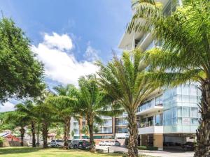 a building with palm trees in front of it at Chic Residences at Karon Beach in Karon Beach