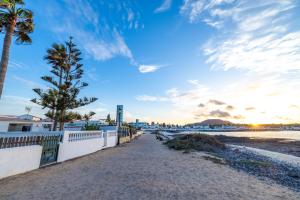 a walkway on the beach with palm trees and the ocean at Villa La Maja Beachfront in Corralejo