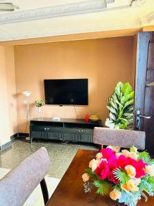 ein Wohnzimmer mit einem TV und einem Tisch mit Blumen in der Unterkunft Exclusive 3BR City Escape High End Comfort & Stunning Views in Daressalam