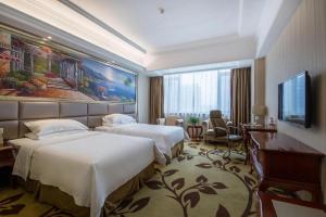 ein Hotelzimmer mit zwei Betten und einem Flachbildfernseher in der Unterkunft Vienna International Shanghai Nanxiang in Chenjiahang
