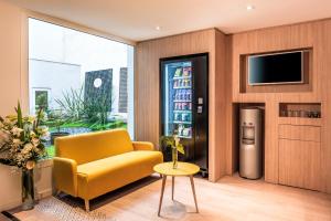 sala de estar con sofá amarillo y TV en Citadines Montmartre Paris, en París