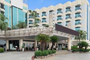 a large building with palm trees in front of it at Excemon Beach Hotel Beihai in Beihai