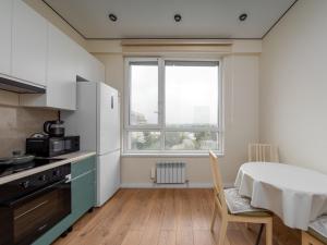 een keuken met een tafel en een groot raam bij Everest Home in Alma-Ata